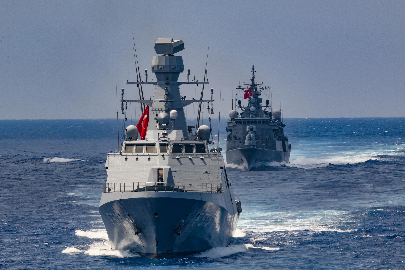 Ada-class corvette TCG Burgazada (F-513), whole foreground vessel at sea; a smaller ship is behind.